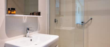 A modern bathroom with a white sink, a glass shower enclosure, and a mirror above the sink.