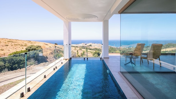 A modern infinity pool with clear blue water, large windows, and a view of the ocean. - Le tanger (Al Bahraoyine)