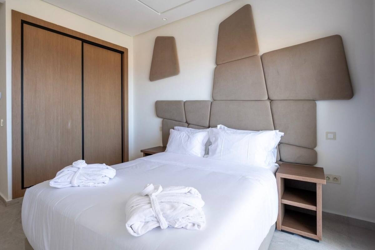 Una habitación de hotel con una cama grande, un armario de madera y un cabecero con diseño geométrico.