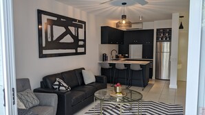 Un salon moderne avec un canapé noir, une table basse en verre et un tapis rayé noir et blanc.