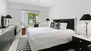 Une chambre à coucher moderne avec un grand lit, deux tables de chevet avec des lampes, une commode et un fauteuil.