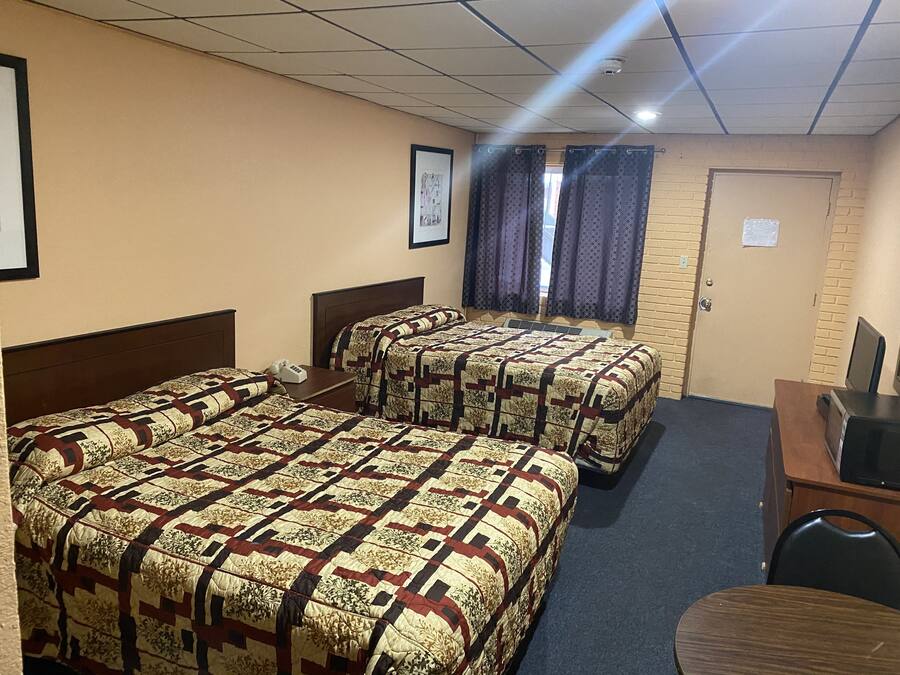 Habitación de hotel con dos camas, un escritorio y una silla.