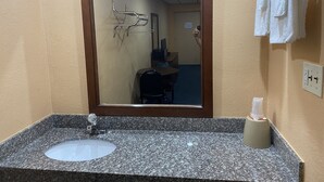 A bathroom with a granite sink, a mirror, a towel rack, and a bottle of hand sanitizer. - Deer Park Motor Inn (Deer Park)