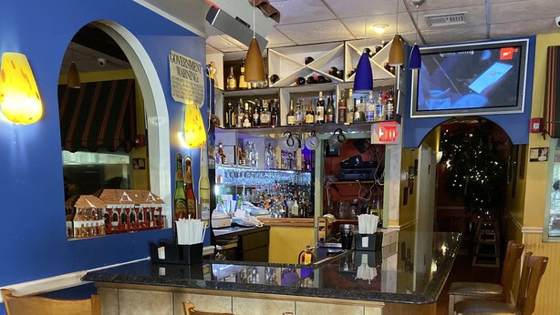 A bar area with a counter, bar stools, and a television screen. - Deer Park Motor Inn (Deer Park)