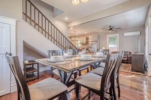A dining area with a large table set for six, surrounded by chairs. A staircase with a railing is visible to the left. - Atchee III: Dog Friendly & Free Bikes (Fruita)