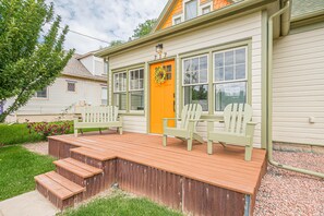 A house with a wooden deck, a bright orange door, and two green Adirondack chairs. - Atchee III: Dog Friendly & Free Bikes (Fruita)