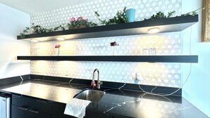 Una cocina moderna con encimeras negras, un lavamanos de acero inoxidable y un salpicadero tipo panal.