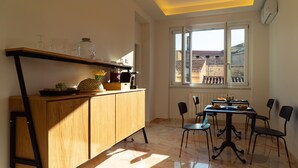Une cuisine moderne avec des meubles en bois, une table à manger avec des chaises et une fenêtre donnant sur des immeubles.