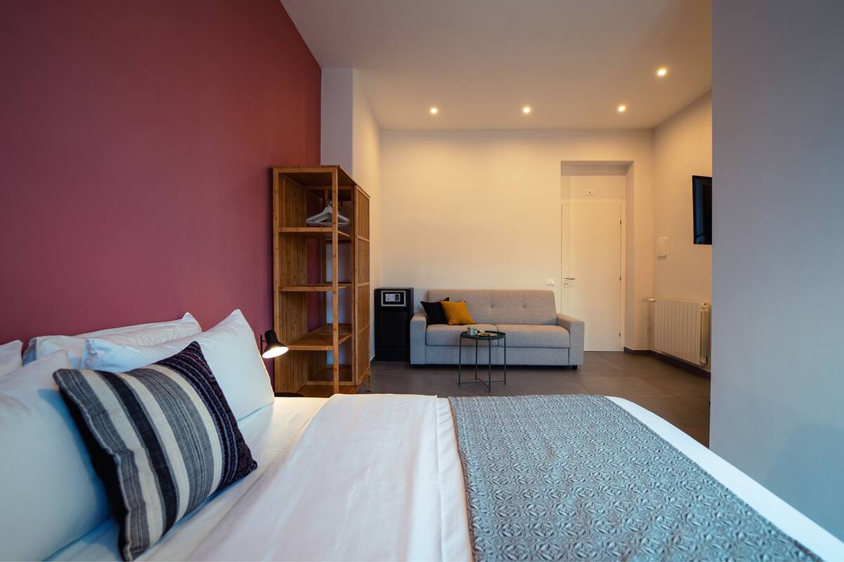 Une chambre d’hôtel moderne équipée d’un lit, d’une armoire, d’un canapé et d’une petite table.