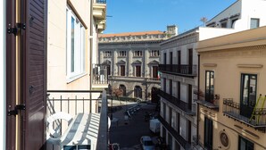 Une vue depuis un balcon donnant sur une rue où sont garés des vélos et sur un bâtiment à l’architecture classique.