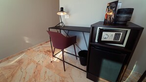 Une petite pièce comprenant un bureau, une chaise, une lampe et un four à micro-ondes.