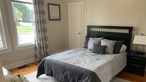 Een netjes opgemaakte slaapkamer met een bed, nachtkastjes en een raam met gordijnen.