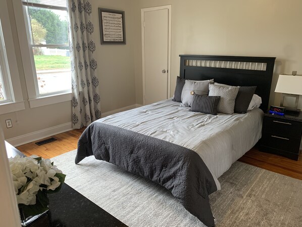 A neatly arranged bedroom with a bed, bedside tables, and a window with curtains.