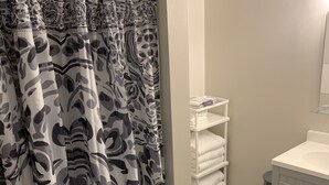 Een badkamer met douchegordijn, toilet, wastafel en spiegel.