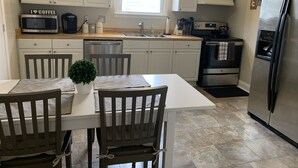 Een moderne keuken met witte kastjes, een roestvrijstalen koelkast en een eethoek met een tafel en stoelen.
