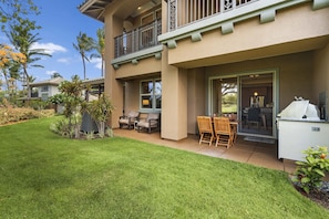 A two-story building with a covered patio area, outdoor seating, and a grill.