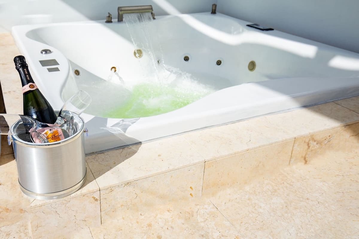 Un jacuzzi con una botella de champán y copas en un balde.