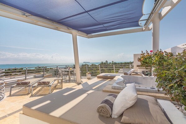 Une terrasse sur le toit offrant une vue sur l’océan, des sièges extérieurs et un jacuzzi.
