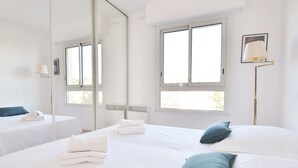 A hotel room with two beds, a large mirror, and a window. - 3-Br. Apartment, Sea View, Swimming Pool. (Cannes)
