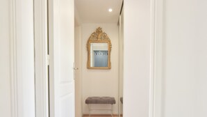A hallway with a bench, a mirror with a decorative frame, and a door. - 3-Br. Apartment, Sea View, Swimming Pool. (Cannes)