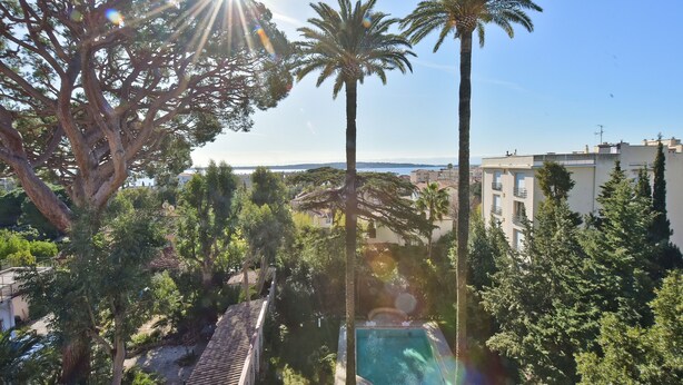 A pool area surrounded by palm trees and a view of the sea. - 3-Br. Apartment, Sea View, Swimming Pool. (Cannes)