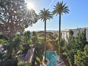A pool area surrounded by palm trees and a view of the sea. - 3-Br. Apartment, Sea View, Swimming Pool. (Cannes)