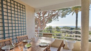 A wooden dining table set with plates, glasses, and cutlery, overlooking a scenic view with trees and a distant landscape. - 3-Br. Apartment, Sea View, Swimming Pool. (Cannes)