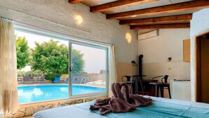 A bedroom with a large window overlooking a swimming pool, a bed with a blue patterned bedspread, and a wooden ceiling. - Wonderful private villa for 8 guests with A/C, private pool, WIFI, TV, patio and pets allowed (Muntic)