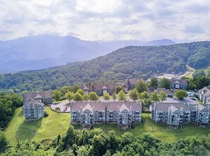 Un quartier résidentiel composé de nombreuses maisons à deux étages, entouré d’une végétation luxuriante et avec des montagnes en toile de fond.