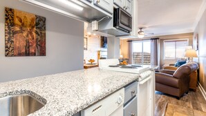 Eine moderne Küche mit Granit Arbeitsplatten, einer Edelstahlspüle und einer Mikrowelle.