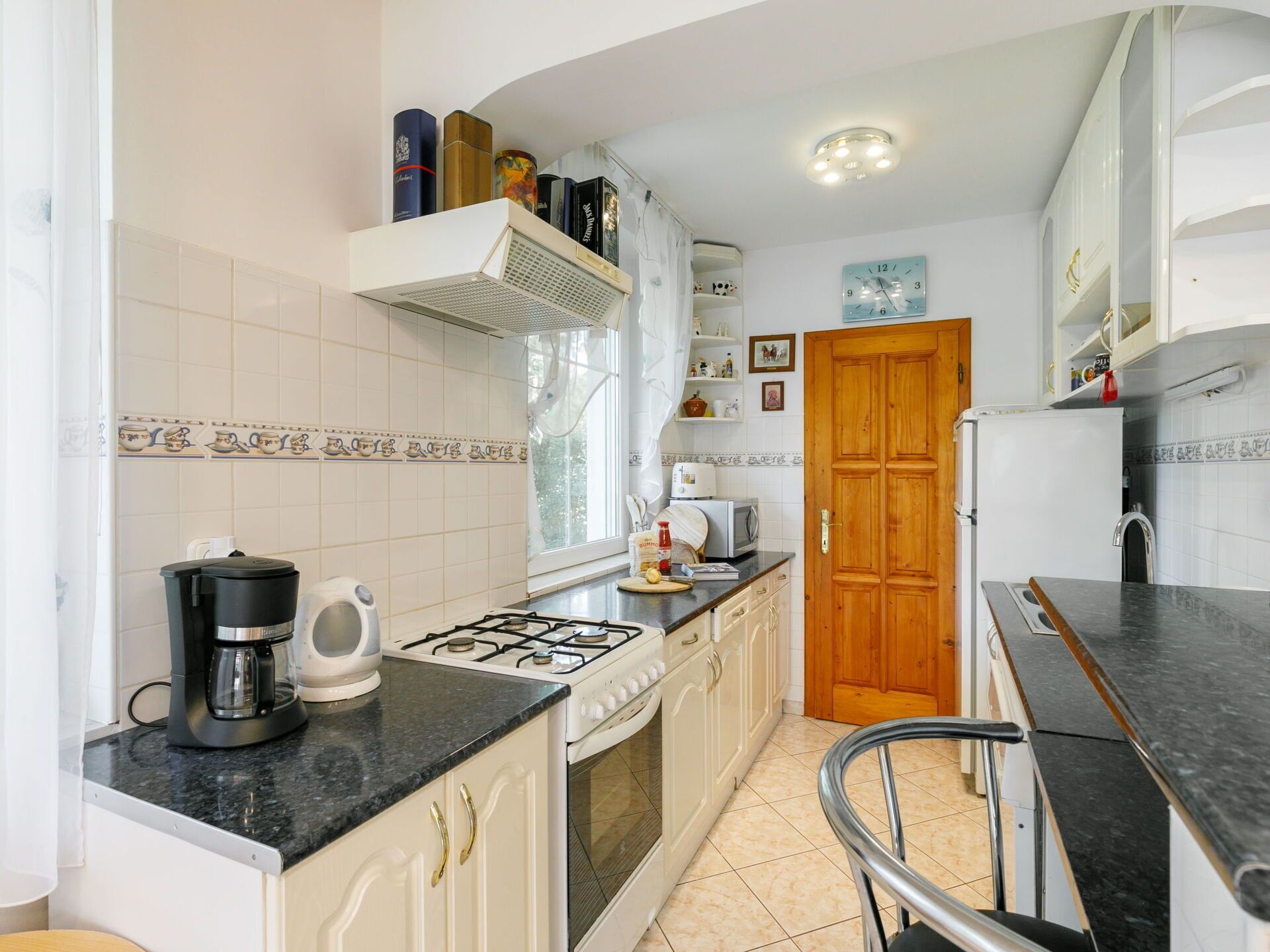 A compact kitchen with white cabinets, a gas stove, a coffee maker, and a microwave.