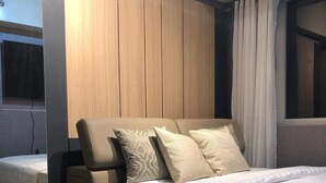 A modern bedroom with a large bed, a wooden headboard, and a flat-screen TV mounted on the wall.