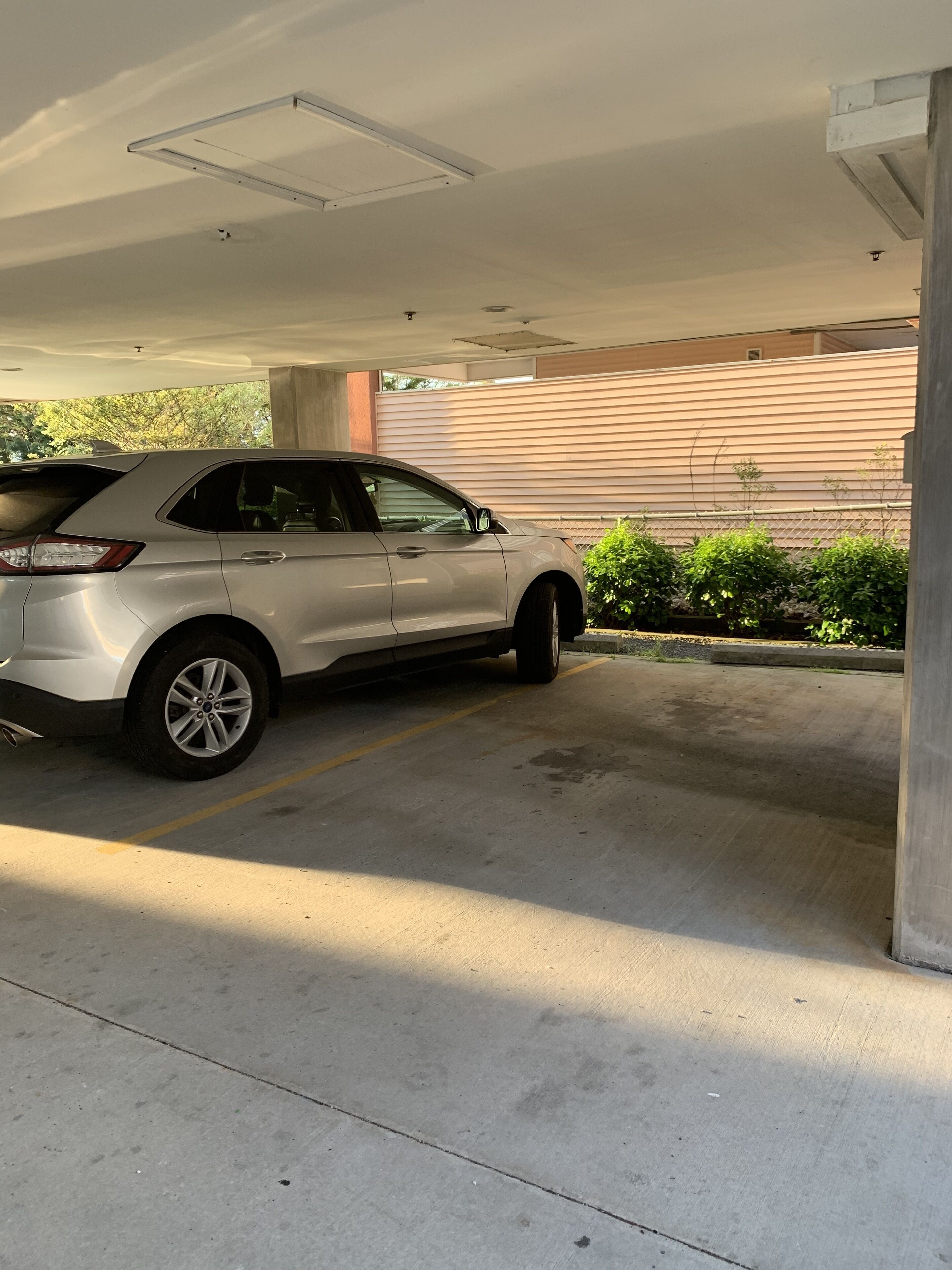 Un garaje para estacionamiento con una camioneta SUV blanca aparcada en un espacio.