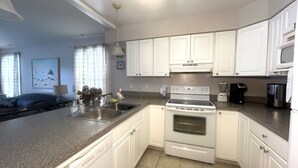 A modern kitchen with white cabinets, a built-in oven, and a coffee maker. - Wilmington Terrace (Ocean City)