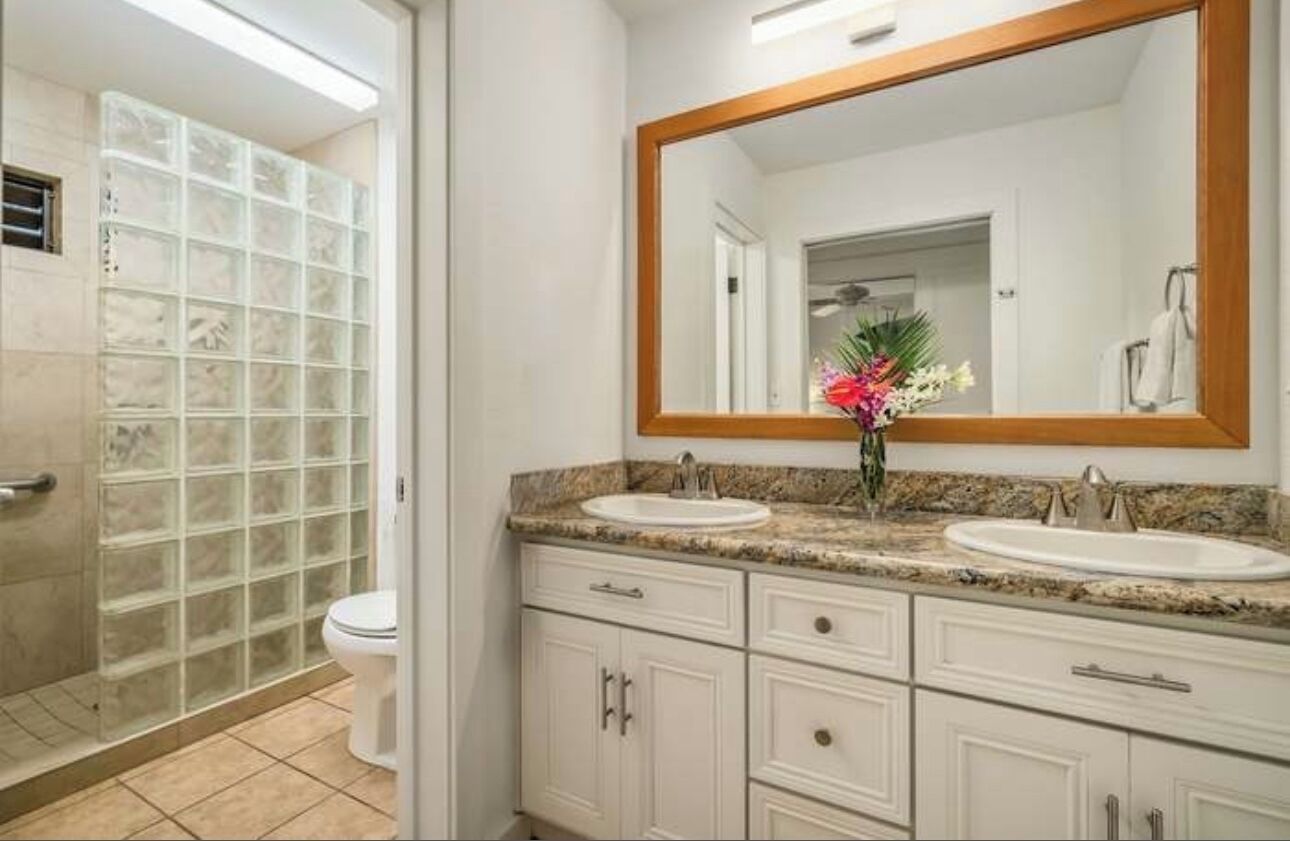 Une salle de bain avec deux lavabos, un grand miroir et une cabine de douche.