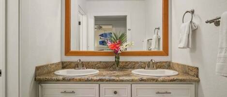 Un baño con dos lavamanos, un espejo grande y un florero con flores.