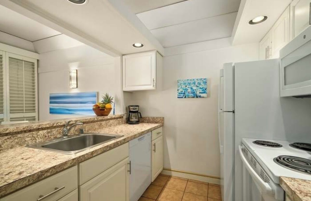 A compact kitchen with a sink, countertop, stove, and cabinets.