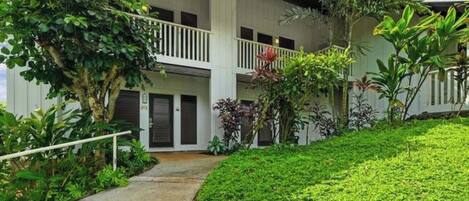 A two-story building with a covered walkway and lush greenery.