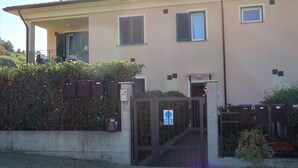 A two-story building with a gated entrance, a small balcony, and satellite dishes on the roof. - Lovely apartment for 4 people with WIFI, A/C, TV, patio and pets allowed (San Bartolomeo Al Mare)