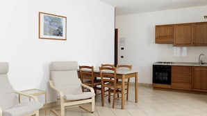 A modern kitchen with wooden cabinets and a dining area with a table and chairs. - Lovely apartment in villa for 4 guests with A/C, WIFI, pool, TV and panoramic view (Bardolino)