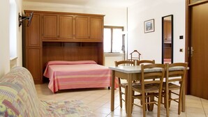 Een slaapkamer met een bed, een tafel, stoelen, een kledingkast en een raam.