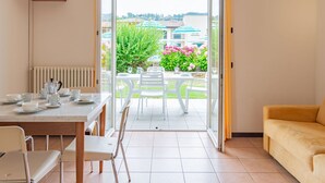 Una habitación con una mesa de comedor dispuesta para cuatro personas, un sofá y un televisor instalado en la pared.