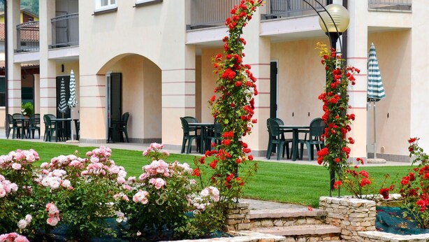 A hotel courtyard with outdoor seating, a stone fountain, and a view of the surrounding buildings. - Lovely apartment for 5 people with A/C, WIFI, pool, TV and patio (Garda)
