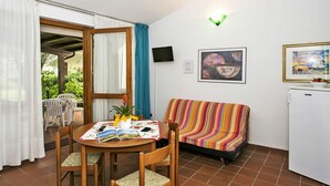 Una habitación pequeña y acogedora con una mesa de comedor, sillas, un sofá, un televisor y obras de arte en las paredes.