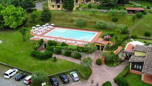 Eine Luftaufnahme eines Hotels mit Swimmingpool, mehreren Gästezimmern und einem Parkplatz.