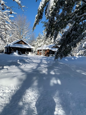 A snow-covered lodge with a clear sky, surrounded by trees.