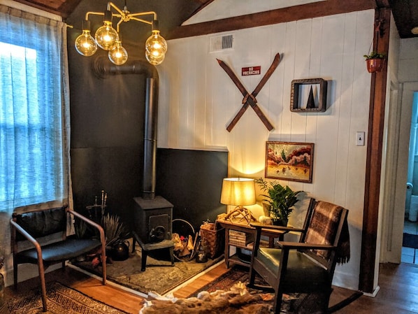 A cozy living room with a fireplace, a bench, a table with a lamp, and a wall-mounted sign.