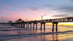 A pier extending into the water with a sunset in the background. - Fabulous DIRECT Oceanfront, private beach, shelling & steps to beach, no traffic (Fort Myers Beach)