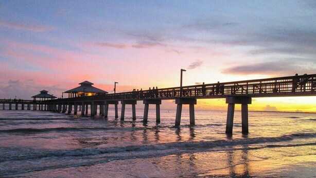 A pier extending into the water with a sunset in the background. - Fabulous DIRECT Oceanfront, private beach, shelling & steps to beach, no traffic (Fort Myers Beach)