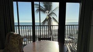 A balcony with a view of the beach, a table, and chairs. - Fabulous DIRECT Oceanfront, private beach, shelling & steps to beach, no traffic (Fort Myers Beach)
